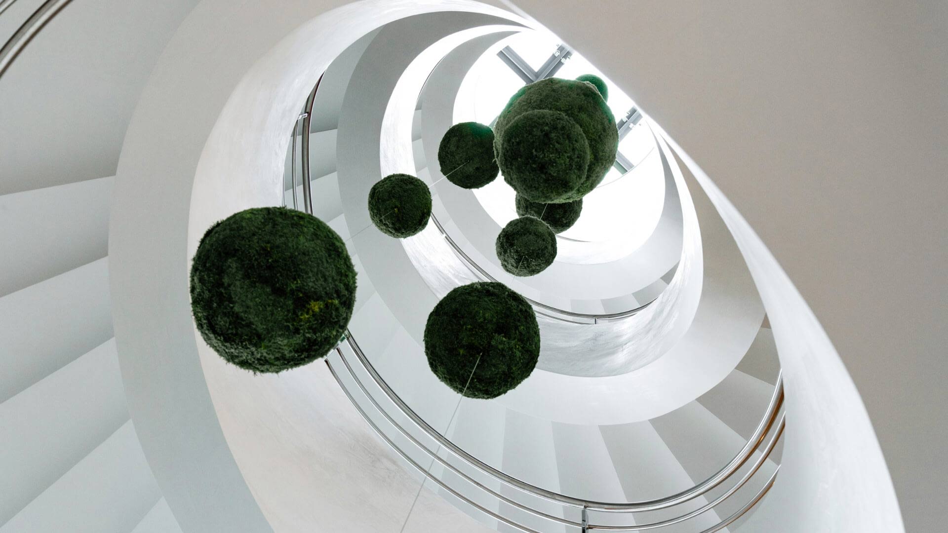 White, round staircase with plants hanging in the middle in the Gdansk office in Poland. 