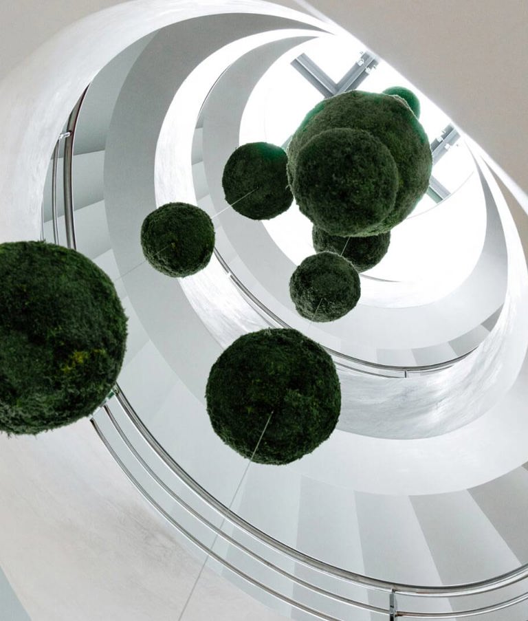 White, round staircase with plants hanging in the middle in the Gdansk office in Poland. 