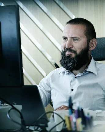 A 7N male staff member looking at a computer while working at the office