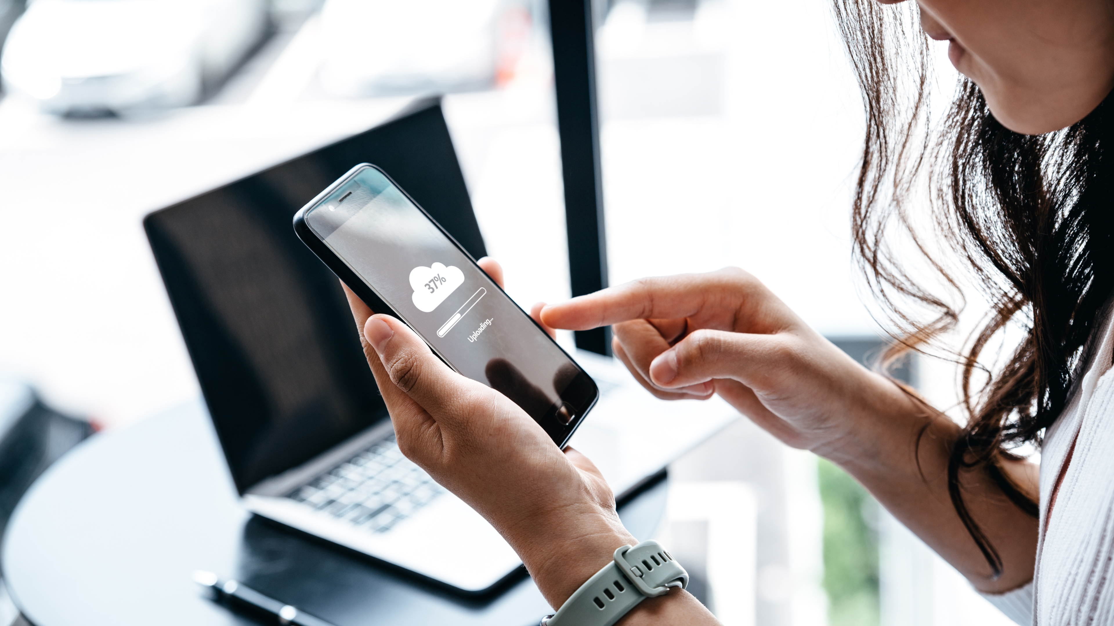 A woman at desk uploading to cloud on phone