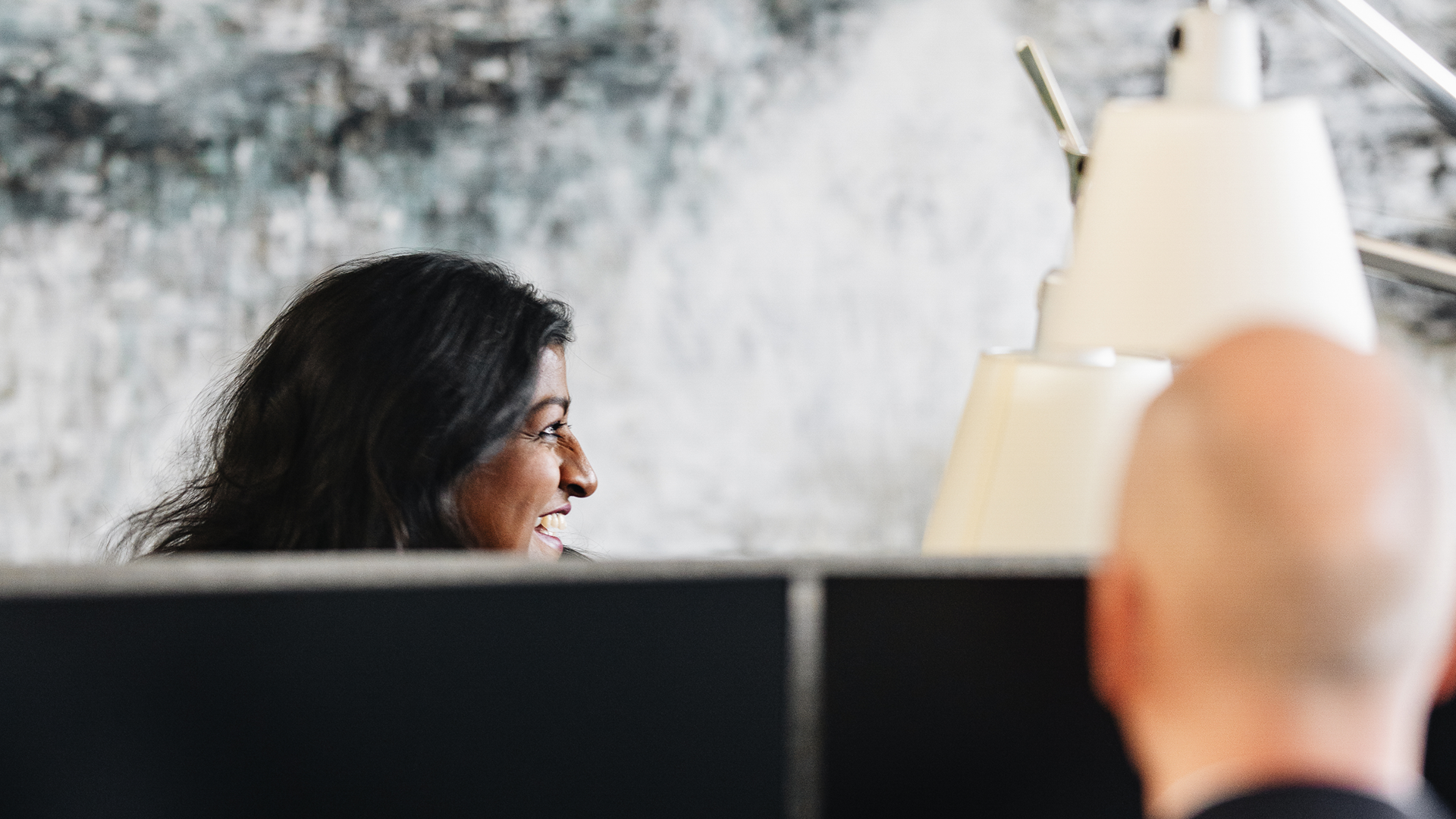 Smiling woman at computer with man across from her in the Copenhagen office in Denmark. 