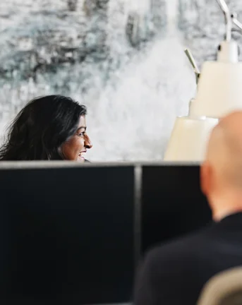 Smiling woman at computer with man across from her