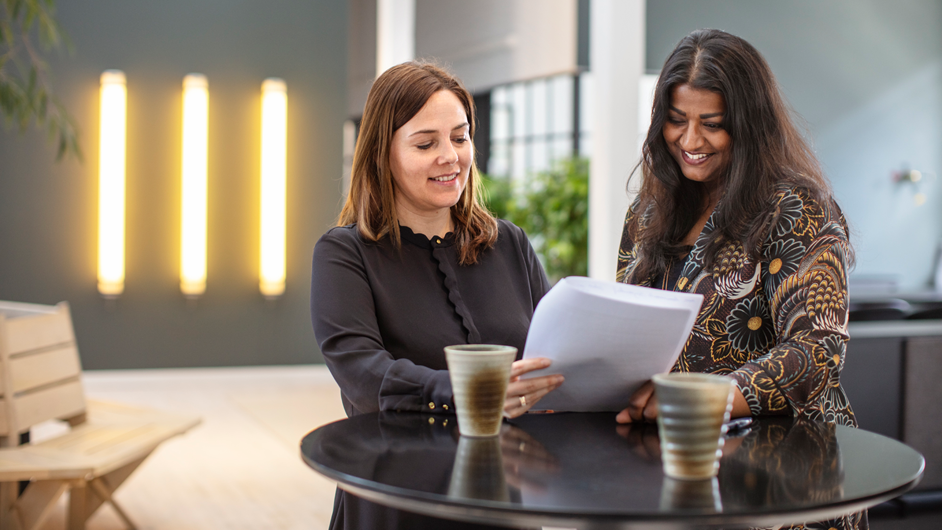 Two 7N employees smiling while looking at a consultant CV in the Copenhagen office in Denmark. 