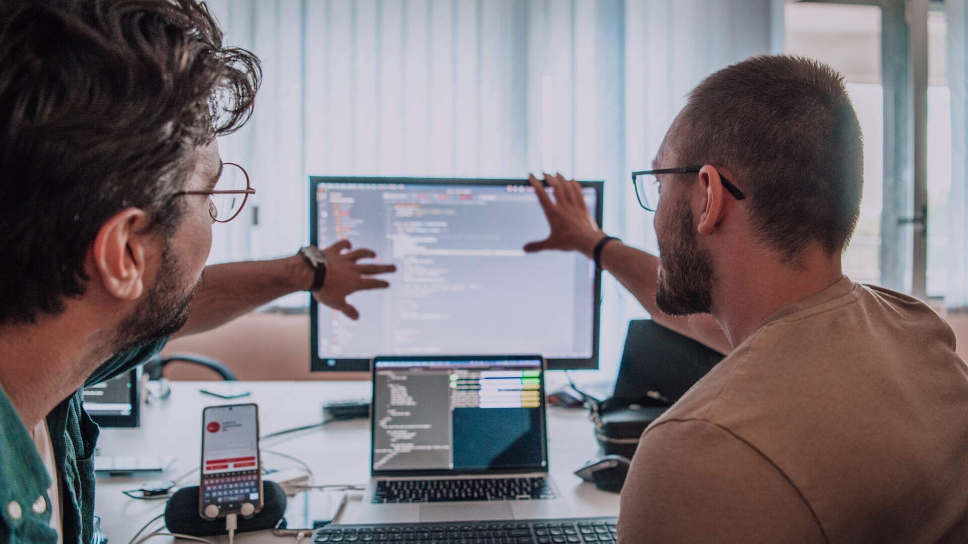 Two people discussing the code on the screens in front of them