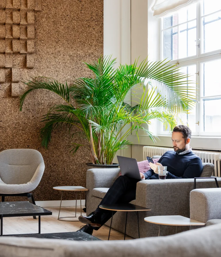 A 7N male staff member working on both the phone and computer while in the office in Copenhagen