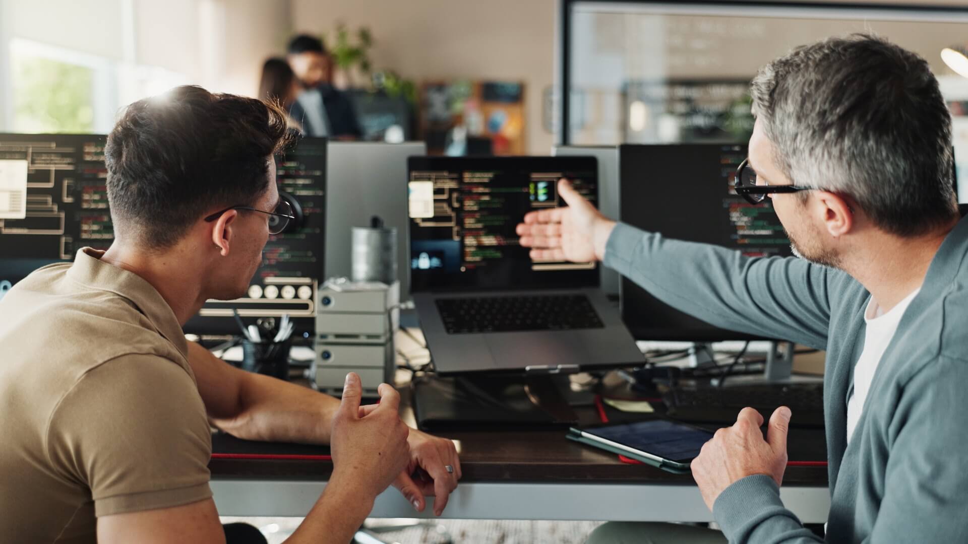 Two developers discussing the code on the screens in front of them