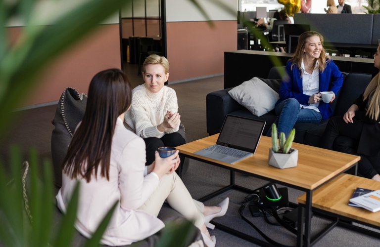 Four women sitting around table while talking