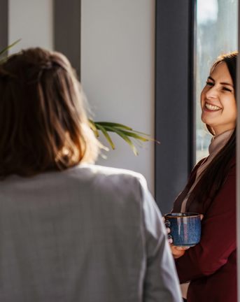 Women talking and smiling in the Gdansk office in Poland. 