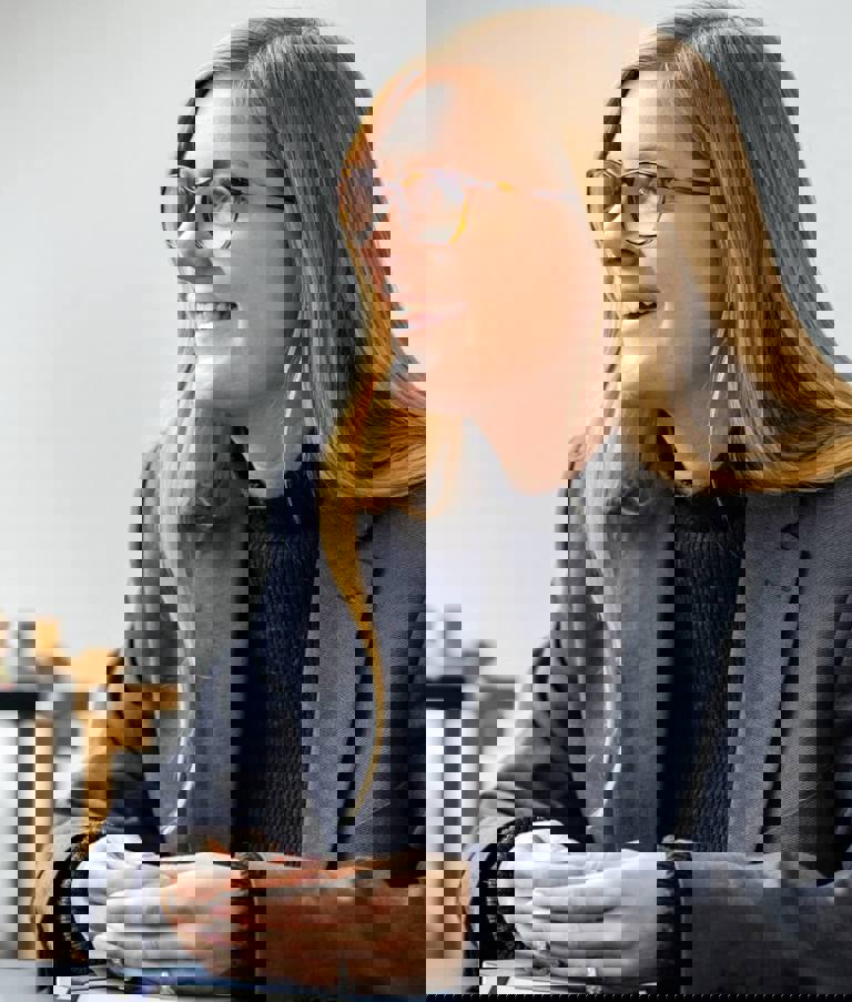 A woman smiling while placing her hands on a book