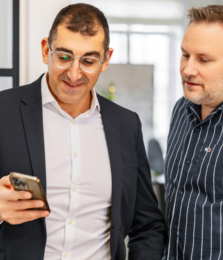 Two men looking at phone in the Copenhagen office in Denmark. 
