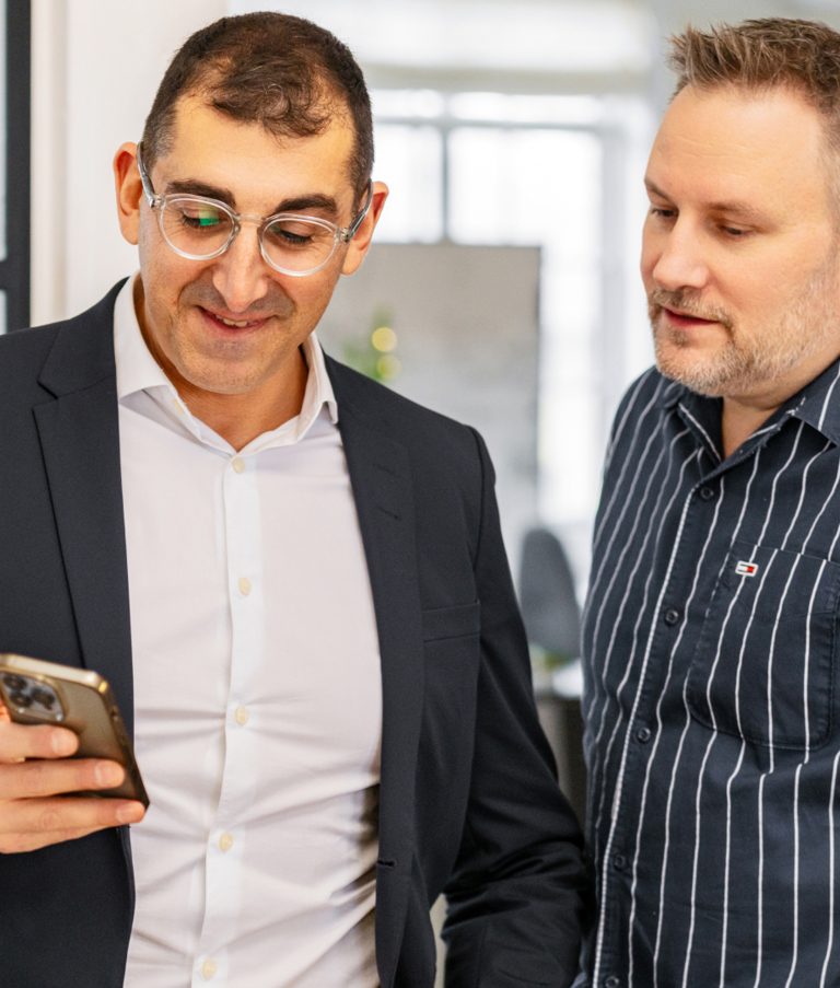 Two men looking at phone in office