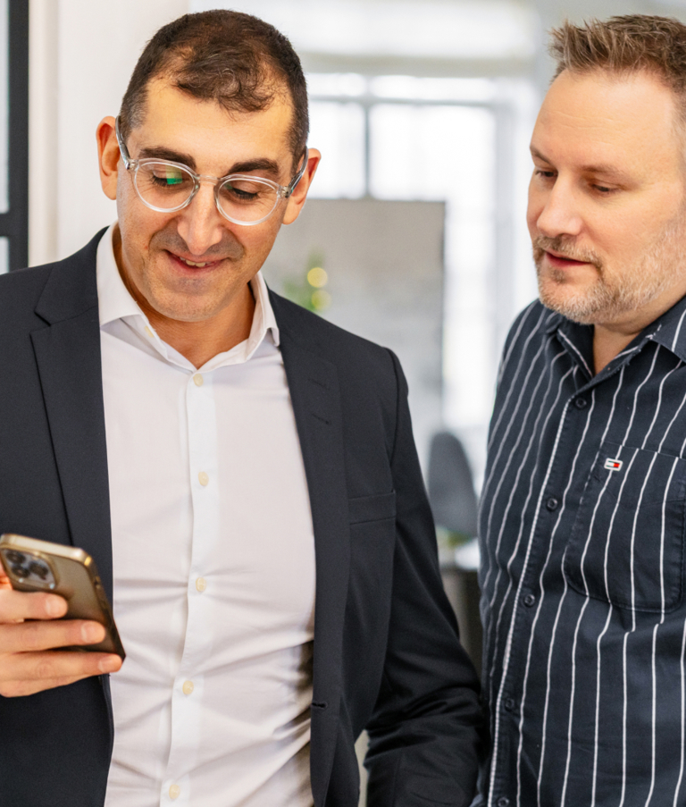 Two men looking at phone in office