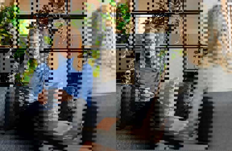 A woman sitting with a cup of coffee while talking to another woman