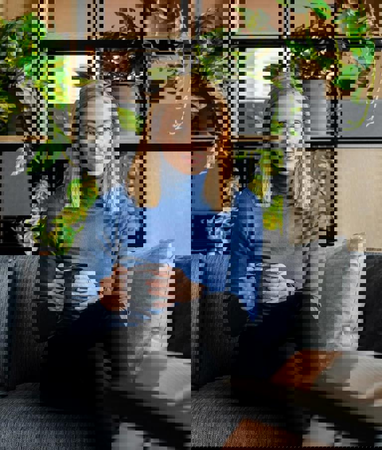 A woman sitting with a cup of coffee while talking to another woman