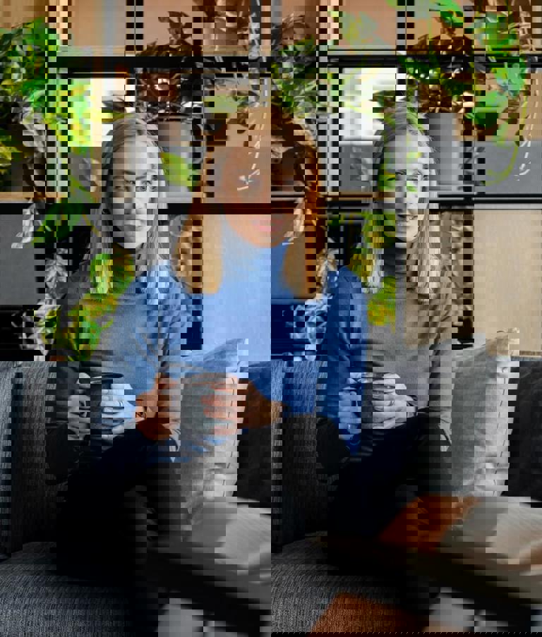 A woman sitting with a cup of coffee while talking to another woman in the Gdansk office in Poland. 