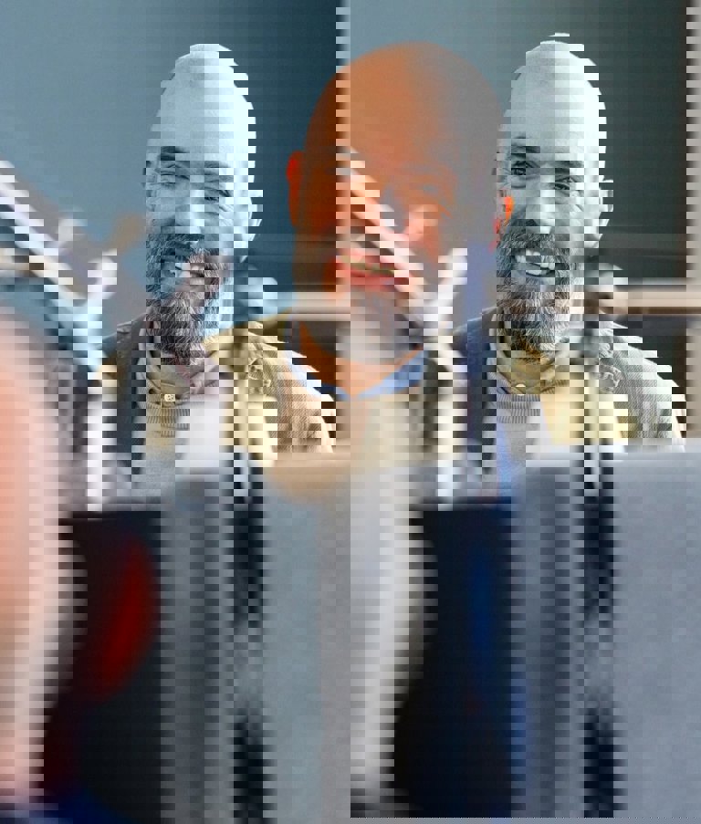 Man in front of computer, smiling at another man