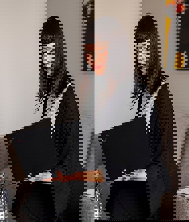 A woman working on her computer while sitting on the sofa