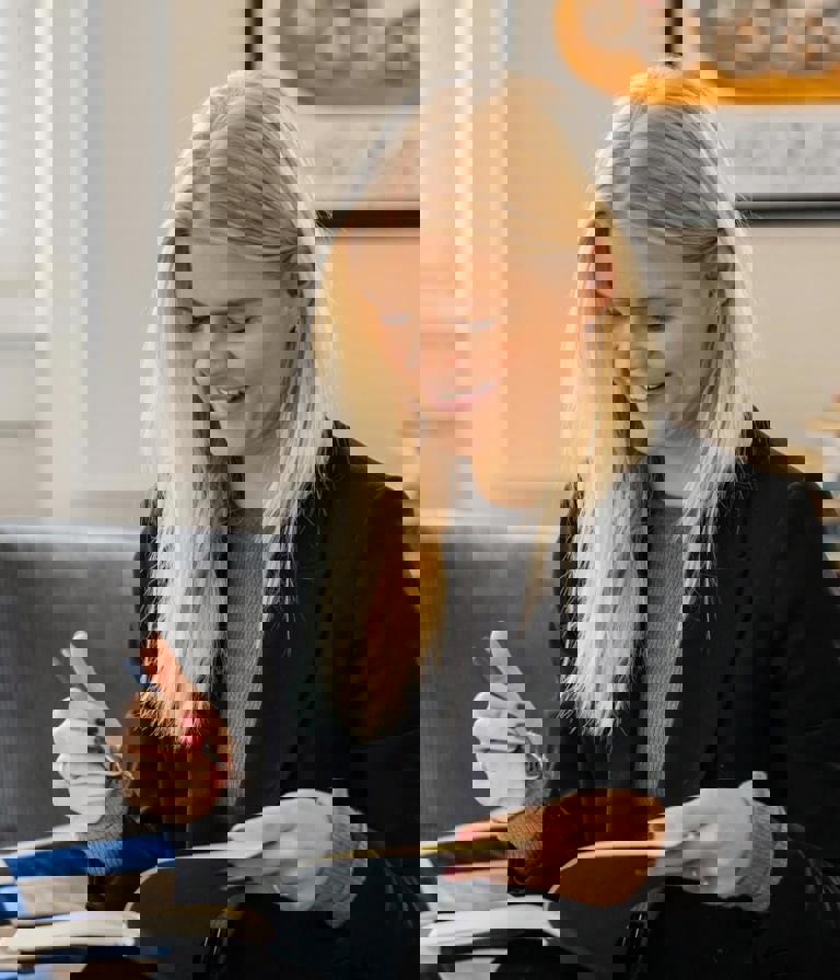 Woman in sofa writing notes in book in the Copenhagen office in Denmark. 