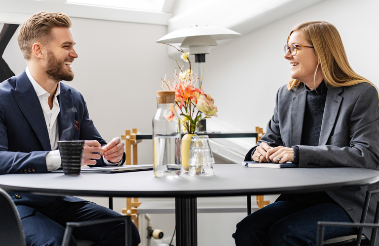 A man and woman sitting beside a black table during a meeting