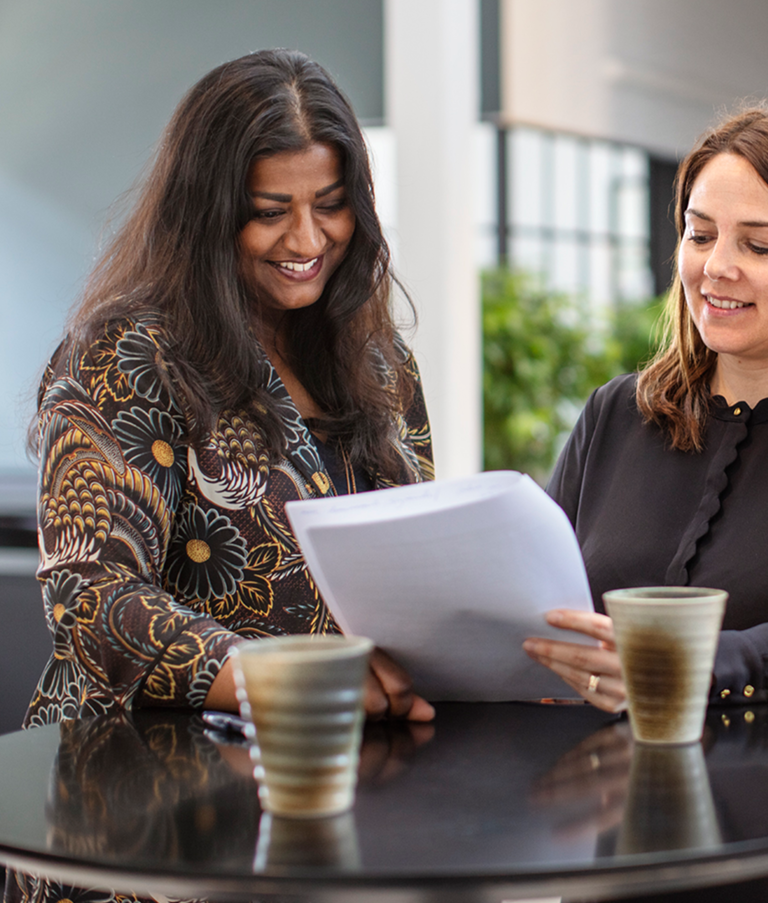 Two 7N employees smiling while looking at a consultant CV in the Copenhagen office in Denmark. 
