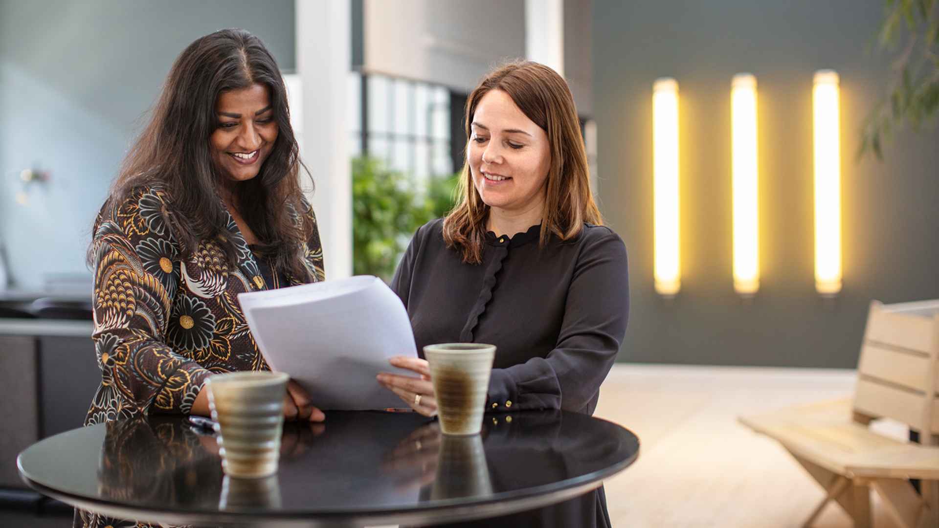Two 7N employees smiling while looking at a consultant CV in the Copenhagen office in Denmark. 