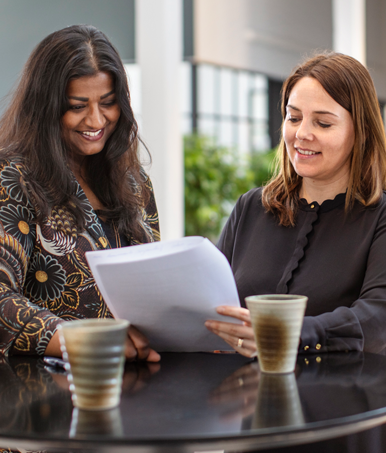 Two 7N employees smiling while looking at a consultant CV in the Copenhagen office in Denmark. 