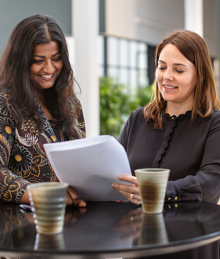 Two 7N employees smiling while looking at a consultant CV in the Copenhagen office in Denmark. 