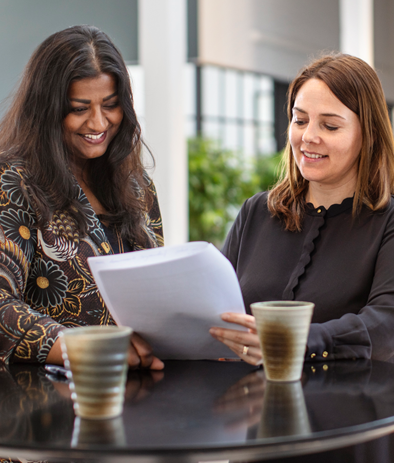 Two 7N employees smiling while looking at a consultant CV in the Copenhagen office in Denmark. 