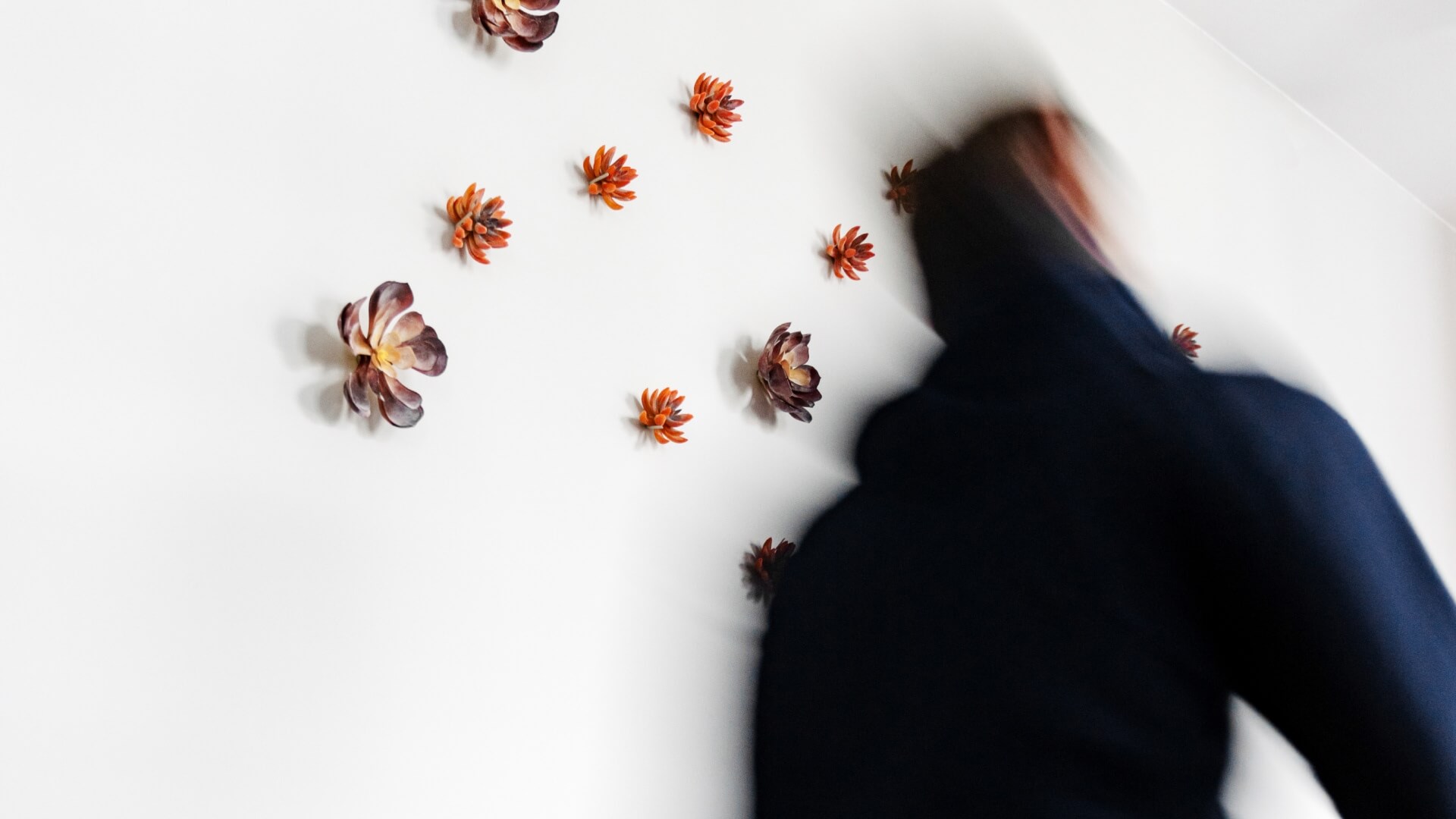 Man walking fast by a white wall with flowers in the Warsaw office in Poland. 