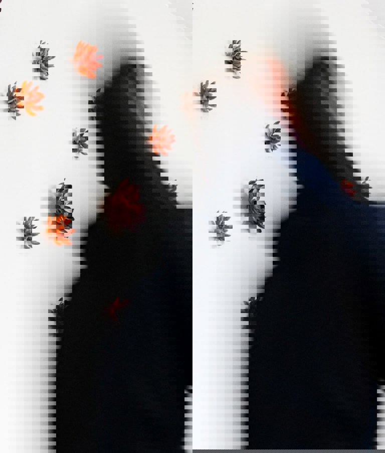 Man walking fast by a white wall with flowers