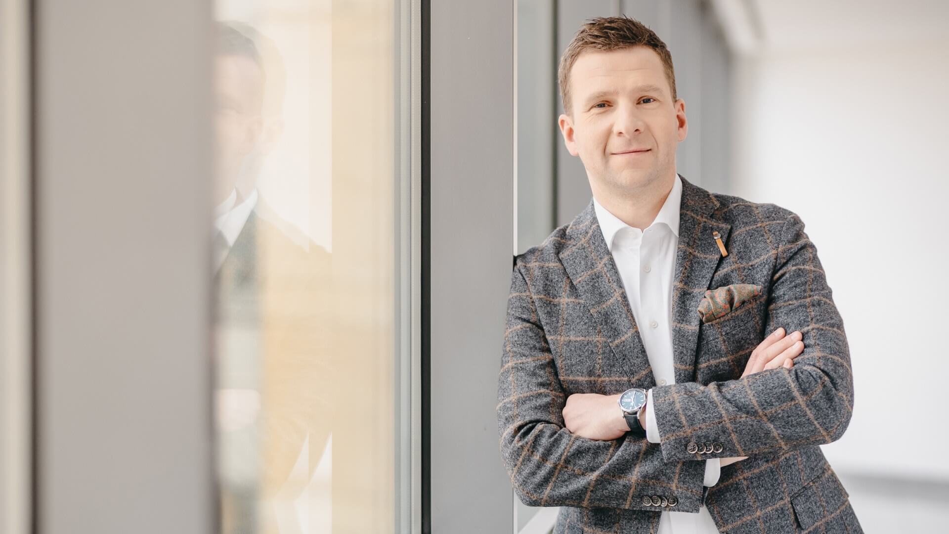 Man in suit standing by a window in the Warsaw office in Poland. 