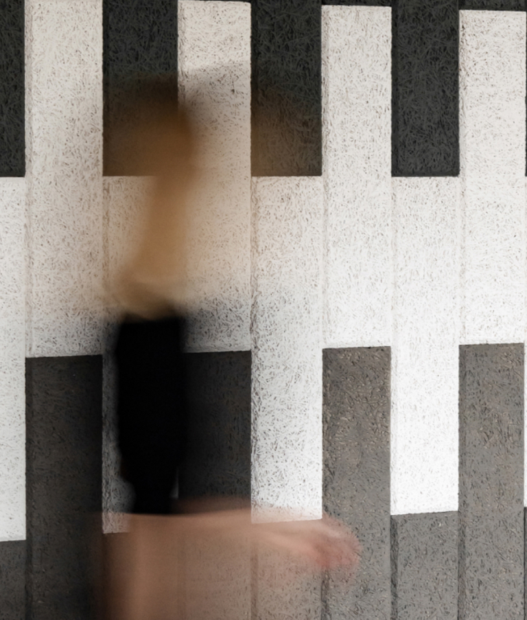 Woman walking past patterned wall