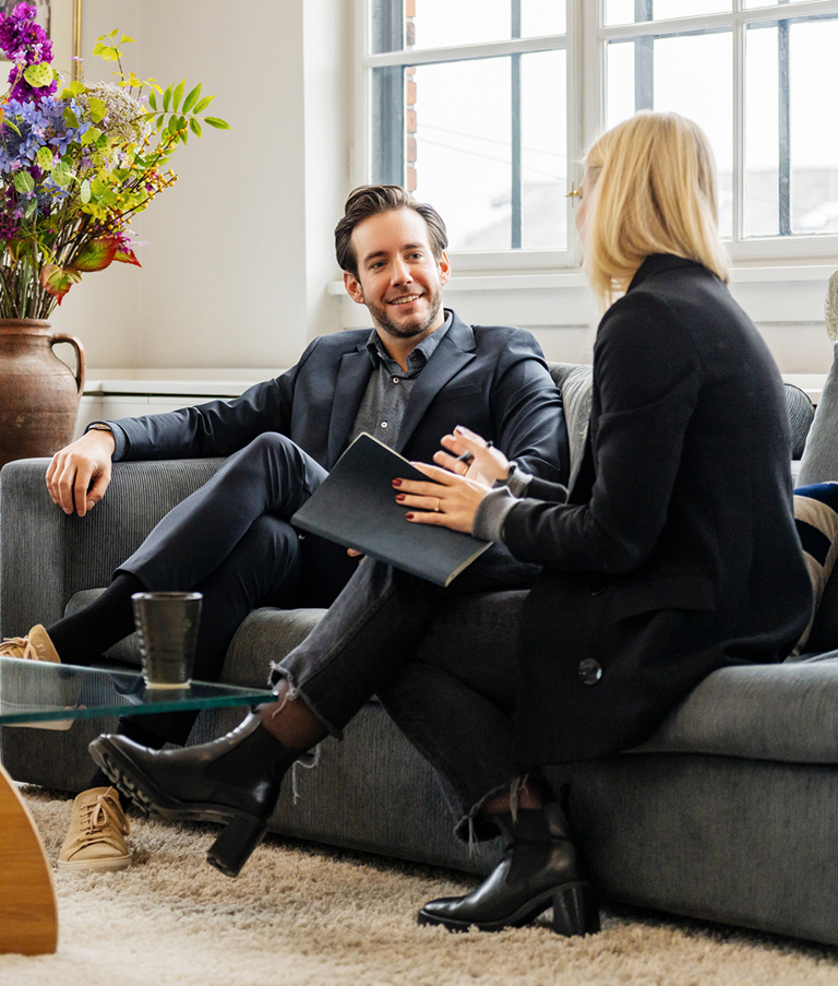 Two men and a woman talking while sitting in sofas 