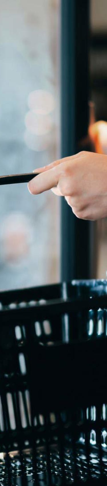 customer shopping with basket while choosing products from refrigerated shelves