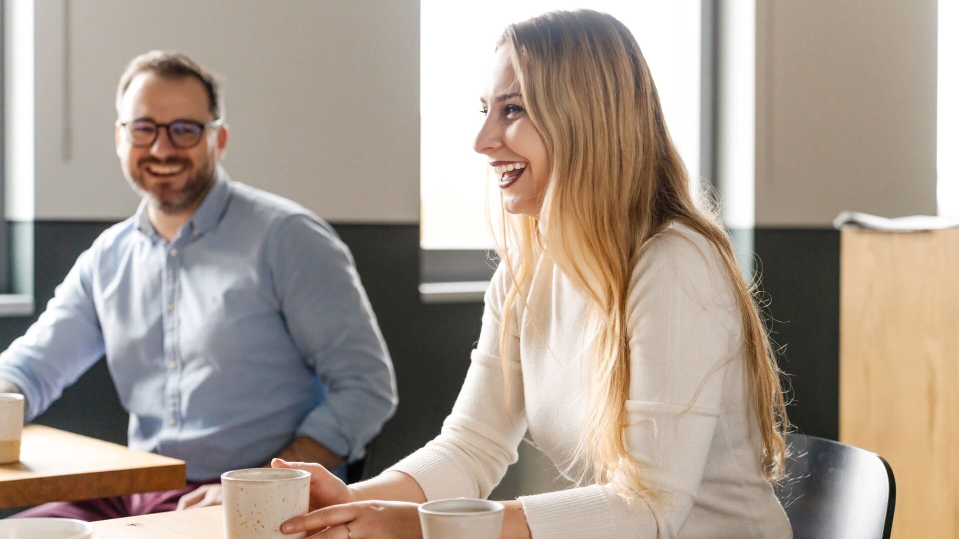 A man and a woman laughing at a table in the Warsaw office, Poland.