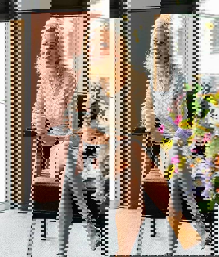 Two women sitting in a grey chairs with a cup of coffee talking in the Gdansk office in Poland. 