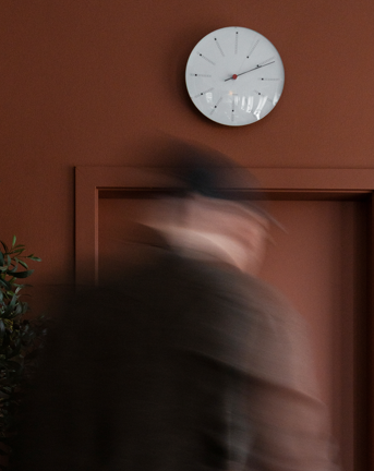 Man walking towards a clock on a red wall in the Copenhagen office in Denmark 