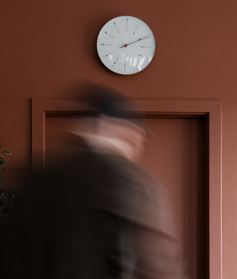 Man walking towards a clock on a red wall