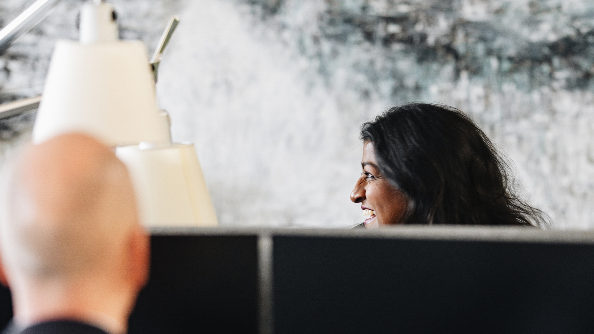 Smiling woman at computer with man across from her in the Copenhagen office in Denmark. 