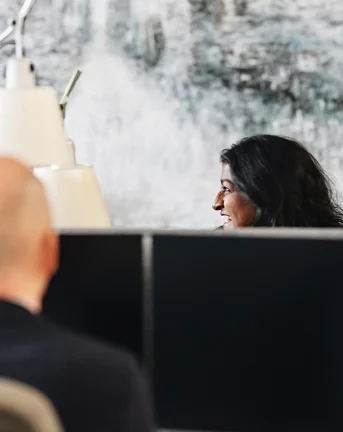 Smiling woman at computer with man across from her